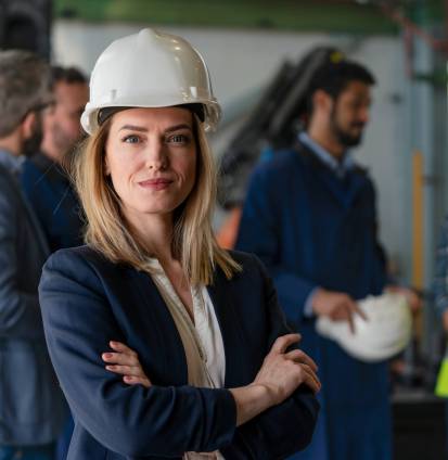 A portrait of female chief engineer in modern industrial factory looking at camera.